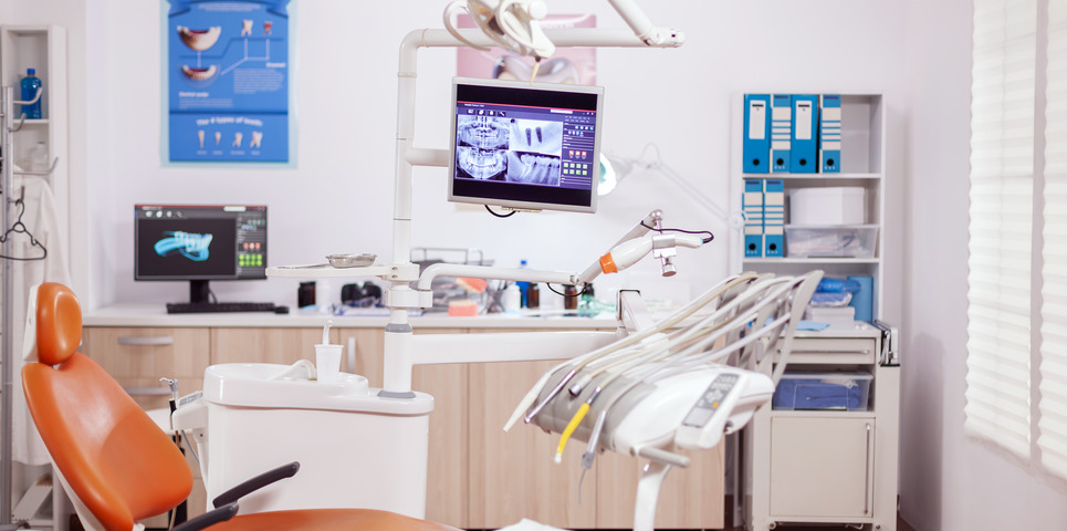 Dental clinic interior with modern dentistry equipment in orange color. Stomatology cabinet with nobody in it and orange equipment for oral treatment.
